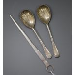A modern silver meat skewer and a pair of silver serving spoons.