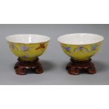 A pair of Chinese Tongzhi yellow ground butterfly bowls, wood stands diameter 11cm