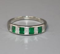 A modern white metal and nine stone emerald and diamond set half eternity ring, set with emerald and