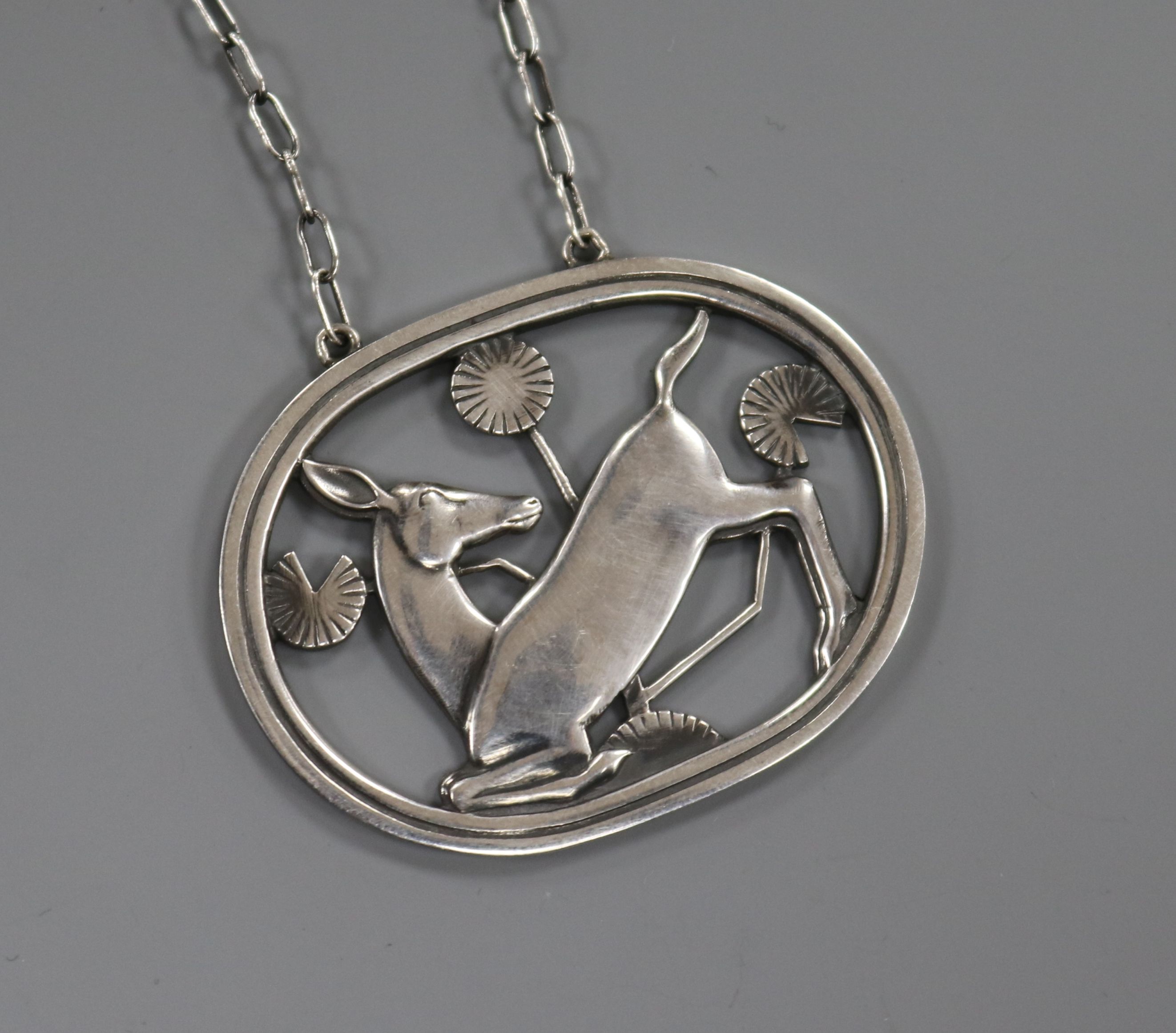 A Danish Georg Jensen sterling silver oval kneeling deer brooch, no. 95, 45mm, on a white metal