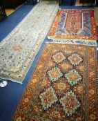 A Persian burnt orange ground rug, centred by six pale green lozenges and two other rugs,