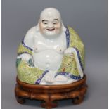 A Chinese enamelled porcelain figure of Budai, wood stand, Guangxu overall height 35cm