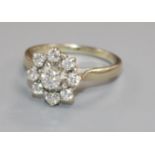 A white metal and nine stone diamond cluster dress ring, size X.