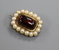 An early Victorian yellow metal, cabochon garnet and split pearl set mourning brooch, 26mm.