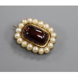 An early Victorian yellow metal, cabochon garnet and split pearl set mourning brooch, 26mm.