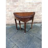 A MAHOGANY DEMI-LUNE FOLD OVER TEA TABLE the four turned tapering supports with pad feet, height