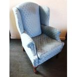 A WING ARMCHAIR upholstered in pale blue and on claw and ball frontal supports