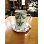A CONTINENTAL CERAMIC TANKARD AND SAUCER with painted floral decoration and gilt highlight, the