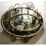 AN ORNATE OVAL WALL MIRROR with central bevelled section, the gilt gesso frame with ribbon and