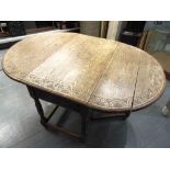 AN OVAL LIGHT OAK GATELEG TWO LAP DINING TABLE carved with lunettes, the turned supports joined by