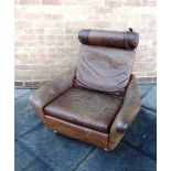 A BROWN LEATHER ARMCHAIR with cylindrical bolster cushion to top, unmarked but probably Danish