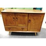 A SMALL ERCOL LIGHT ELM SIDEBOARD with cupboard above drawer beside further cupboard, 114cm wide