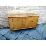A GORDON RUSSELL STYLE SIDEBOARD fitted with four drawers flanked by cupboard, with brass knob