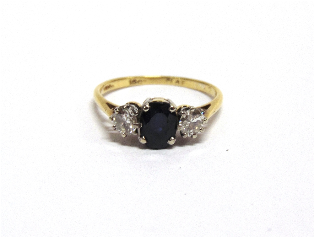 A THREE STONE SAPPHIRE AND DIAMOND RING stamped '18k', the oval cut stone flanked by brilliant cut