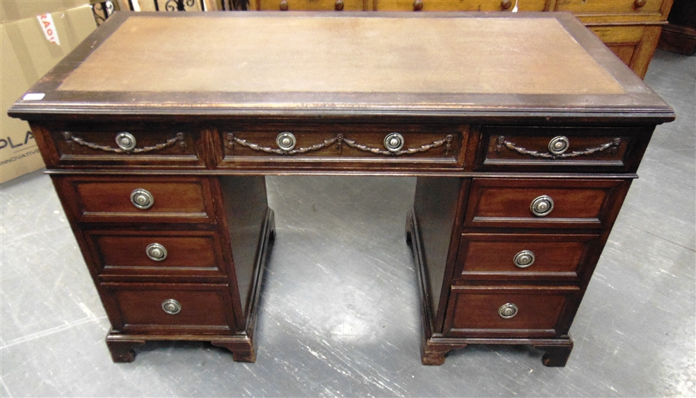 AN EDWARDIAN MAHOGANY TWIN PEDESTAL DECK with swag decoration to the three frieze drawers, 125cm