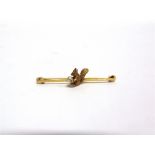 A SQUIRREL BAR BROOCH stamped '15ct', holding a simulated pearl 'nut' in its paws, 4.9cm long, 3.