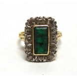 AN EMERALD AND DIAMOND 18 CARAT GOLD CLUSTER RING the rectangular cut stone enclosed by twelve old