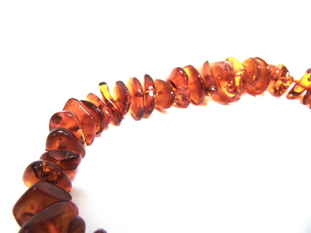 A GRADUATED ROW OF TUMBLED AMBER BEADS 49cm long, 54g gross