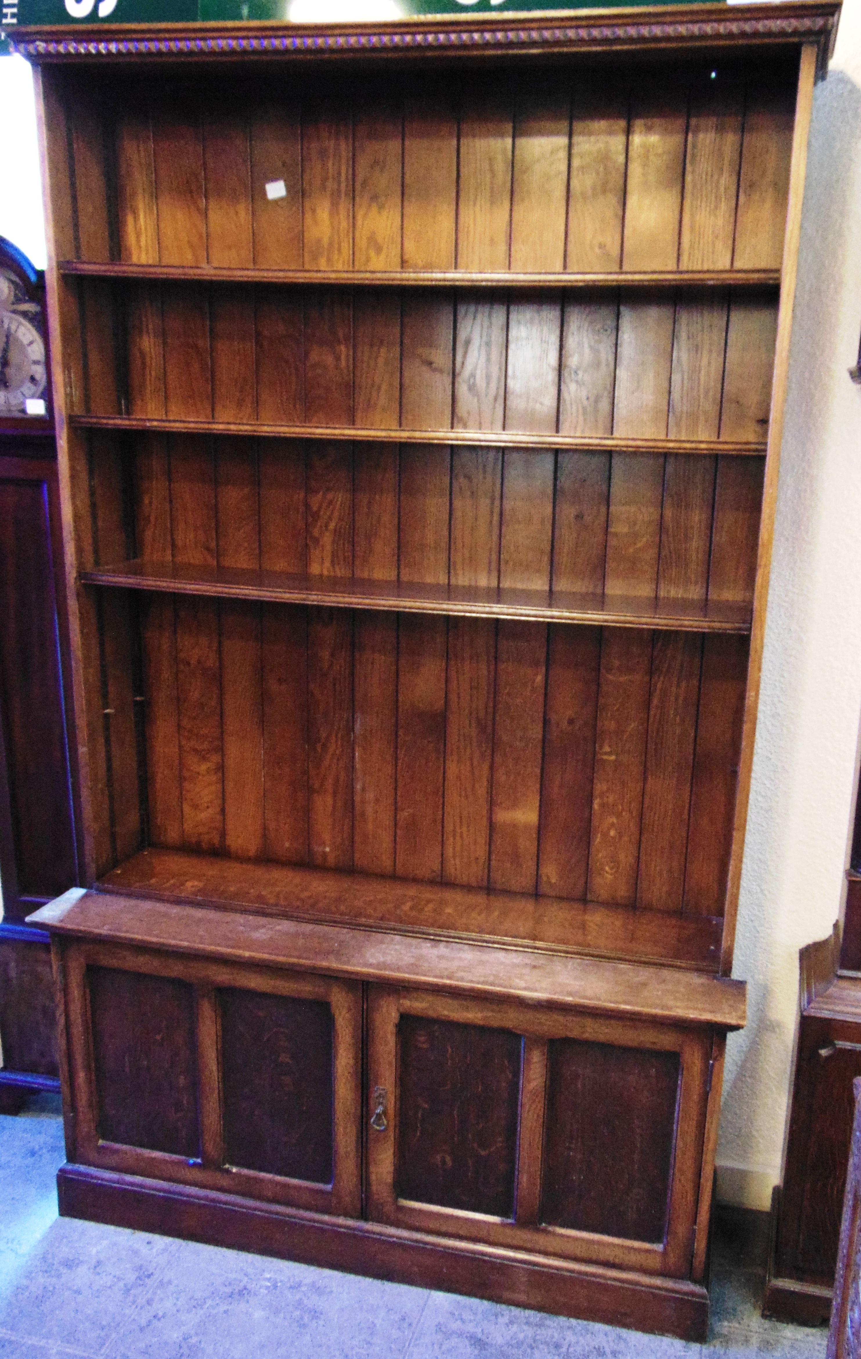 A LARGE OAK OPEN BOOKCASE fitted with four adjustable shelves above cupboard to base, 121cm wide