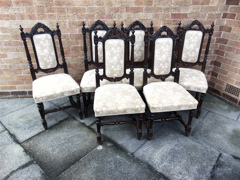 A SET OF SIX CARVED OAK DINING CHAIRS with upholstered seats and backs, on H-shape stretcher bases