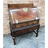 AN EARLY 20TH CENTURY OAK BUREAU with carved decoration and two pairs of drawers, the upper