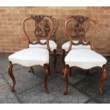 A SET OF FOUR VICTORIAN UPHOLSTERED SIDE CHAIRS with carved balloon backs serpentine front stuffover