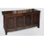 A 17TH CENTURY OAK COFFER the four panel front with carved decoration, on stile feet 157cm wide 62cm