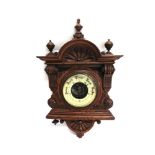 AN EDWARDIAN ANEROID BAROMETER in carved oak case, 30cm wide 47cm high