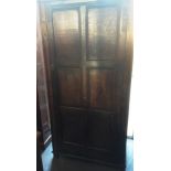 A PANELLED OAK WARDROBE with moulded cornice and carved frieze, single door opening to hanging