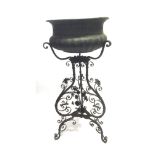 AN EMBOSSED METAL JARDINIERE 41CM DIAMETER on a wrought iron stand with foliate decoration, 95cm