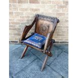 A CARVED OAK GLASTONBURY CHAIR the back centred with a roundel, the arms and backrail with carved