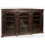 A 19TH CENTURY CARVED OAK GLAZED SIDE CABINET the triple arched glazed doors opening to three