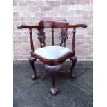 A CARVED MAHOGANY CORNER ARMCHAIR with two carved and pierced splats, on cabriole supports united by