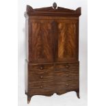 A GEORGE III MAHOGANY LINEN PRESS the frieze with carved pinecone and fan motifs, above panelled