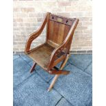 AN OAK GLASTONBURY CHAIR of typical form, with brass plaque and two pierced trefoils to the