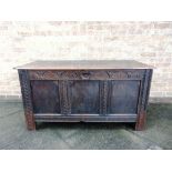 A JOINED OAK COFFER the triple panel front with carved decoration, 138cm wide 57cm deep 72cm high