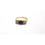 A SYNTHETIC RUBY AND DIAMOND THREE STONE RING stamped '18ct', the two brilliant cuts totalling