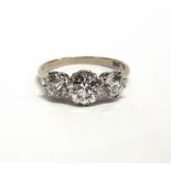 A THREE STONE DIAMOND RING the white mount stamped '18ct', the graduated old cuts calculated as