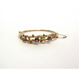 AN EDWARDIAN AMETHYST AND SEED PEARL BANGLE stamped '15' to the catch, the three graduated round