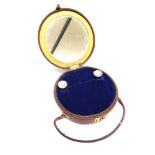 A CIRCULAR LEATHER CASE mirrored to the inside cover and compartments, fitted with two glass balm