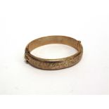 A 9 CARAT GOLD HINGED BANGLE half engraved decoration, inner diameter 6.2cm by 5.5cm, 18g gross