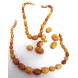 A GRADUATED ROW OF RECONSTITUTED AMBER BEADS the twenty five oval beads of approximately 1.2cm - 2.