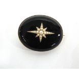 A VICTORIAN MOURNING BROOCH locket back, the split pearl star burst motif against a black ground,