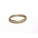 A SPRUNG HINGED BANGLE stamped '375', of pierced design, inner diameter 6.1cm by 5.4cm, 9g gross