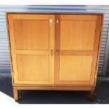 A DANISH TEAK TWO DOOR CABINET on square supports, with exposed finger joint detail to top edges,