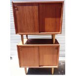 A PAIR OF DANISH TEAK SMALL SIDEBOARDS with sliding doors enclosing shelves and drawers, on tapering