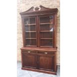 A LATE VICTORIAN MAHOGANY BOOKCASE with swan neck pediment above glazed doors enclosing three