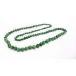 A GRADUATED ROW OF JADE BEADS the one hundred and three beads of approximately 4.5/10mm diameter,