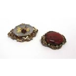 A VICTORIAN AGATE PANEL BROOCH with a cabochon floral motif to the centre, 6cm across; with