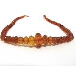 A GRADUATED ROW OF FACETTED AMBER BEADS the seventy five beads of approximately 5.8mm - 9mm, 52cm